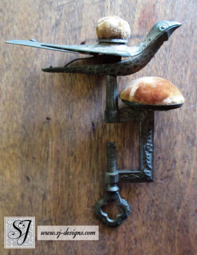 19th century dark brass sewing bird with peach velvet cushions